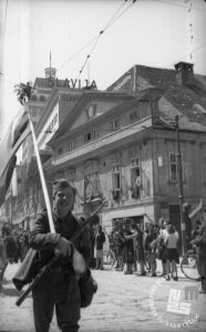 Prihod partizanov pred Figovcem, v ozadju nebotičnik. Foto Rudi Stopar, hrani MNZS.